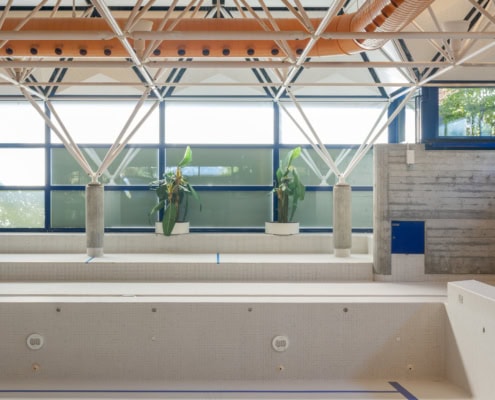 Intérieur d'une piscine vide avec des murs en béton et une structure en acier au plafond.