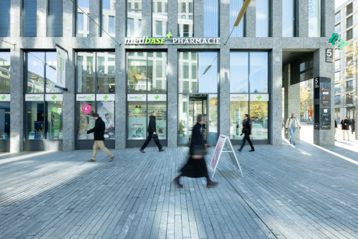 Pharmacie medbase à Lausanne vue de la rue avec passants, moderne et lumineuse.