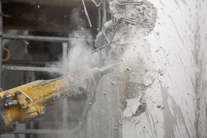 Démonstration de gros œuvre avec machine de démolition en action au chantier.