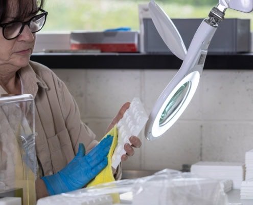 employée en train de passer un chiffon sur des pièces d'usine