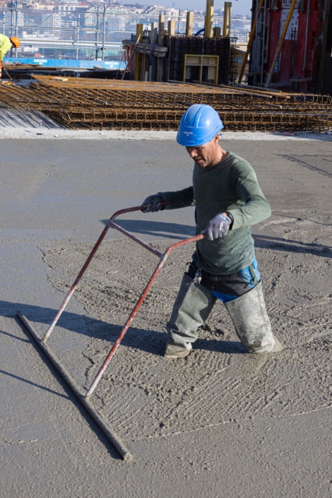 ouvrier de bâtiment en train d'applanir une dalle de béton