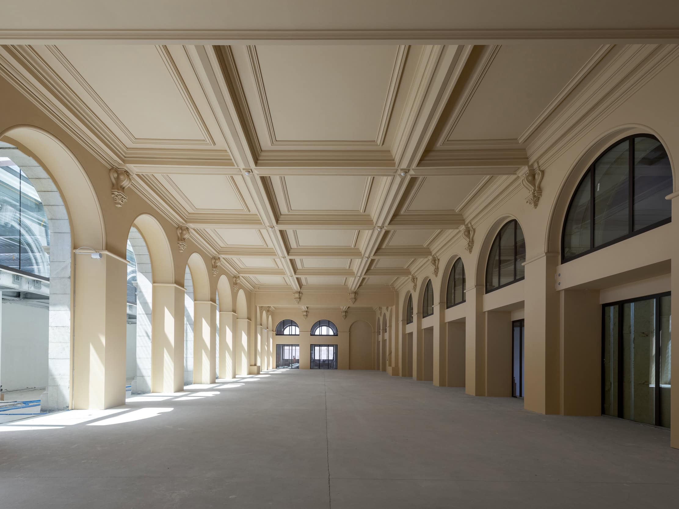 Salle de réception élégante avec hauts plafonds et grandes fenêtres lumineuses.